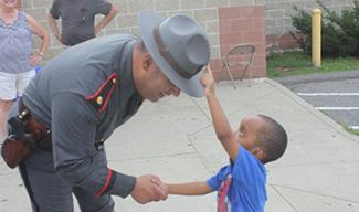 child touching state trooper's hat
